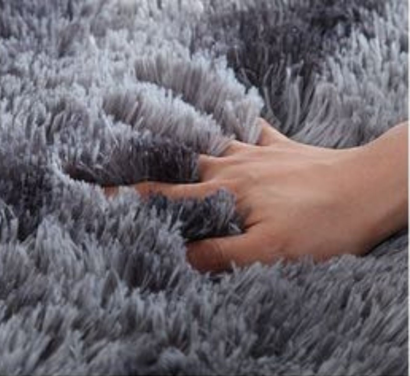 Detailfoto van zacht, fluffy hoogpolig vloerkleed in donkergrijs met lange vezels.