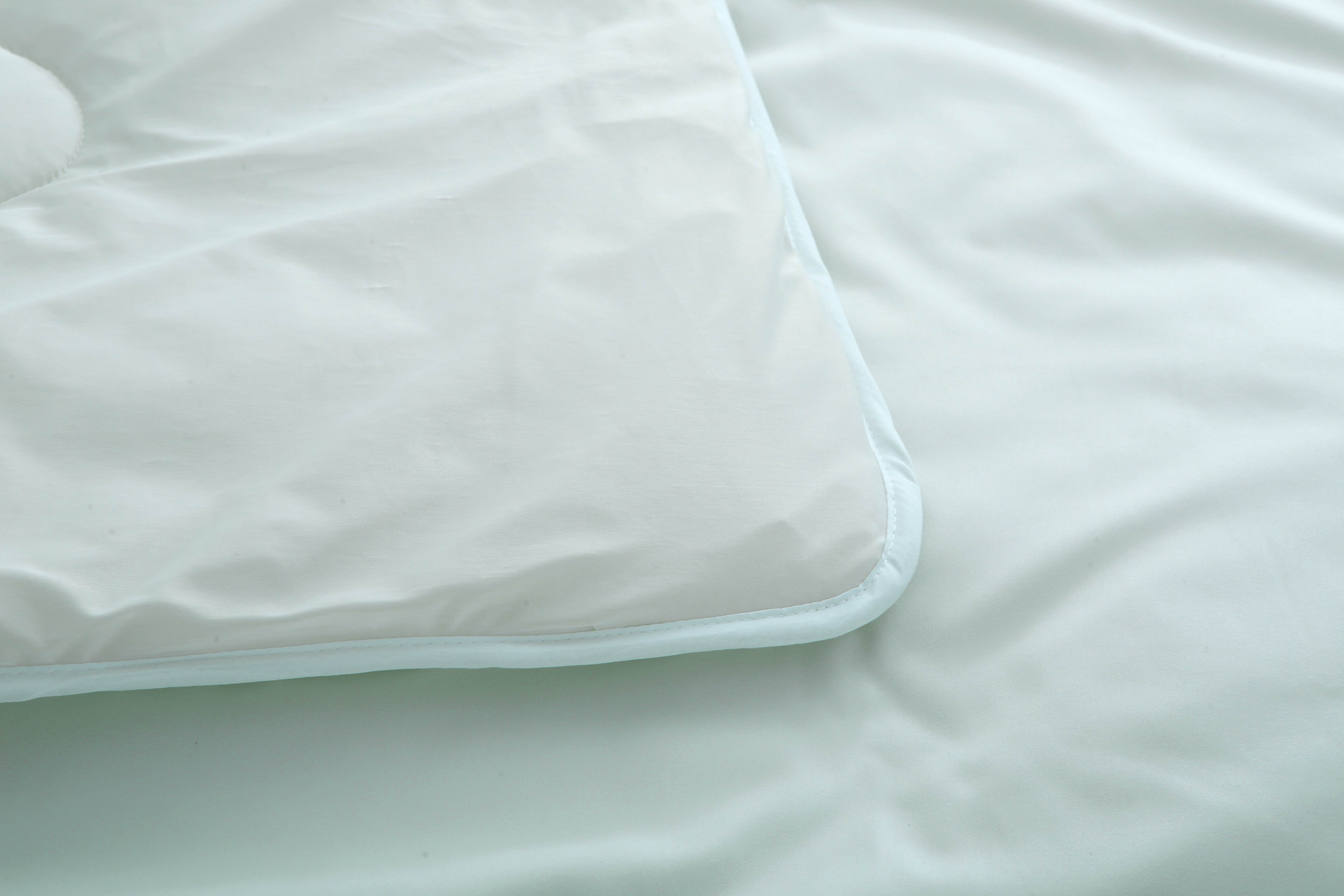 Detail van de hoek en randafwerking van een lichtgroen verkoelend dekbed zonder overtrek