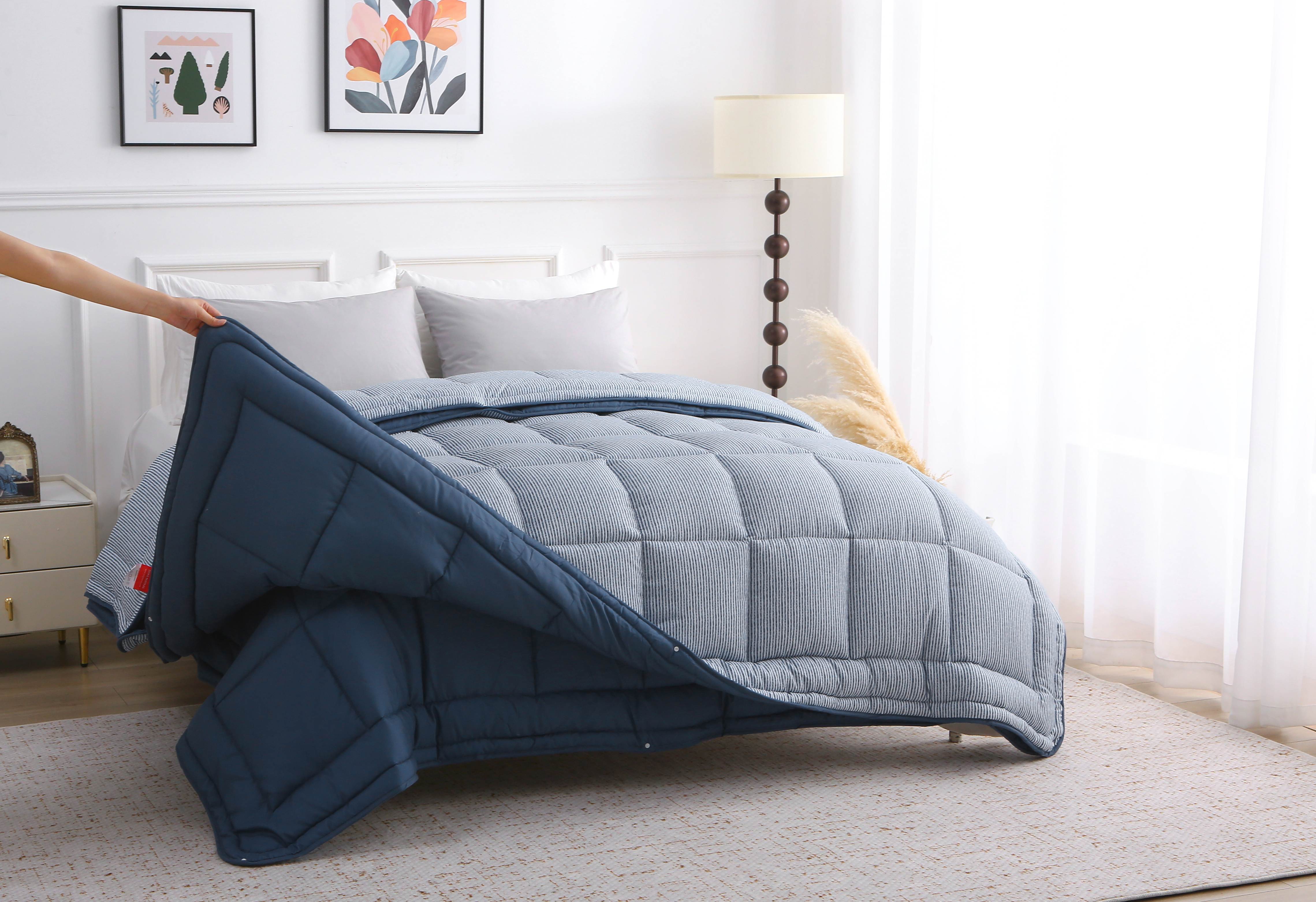 Hand tilt het bovenste deel van het blauwe 4-seizoenen dekbed op om de laagstructuur en vaste hoes te laten zien.
