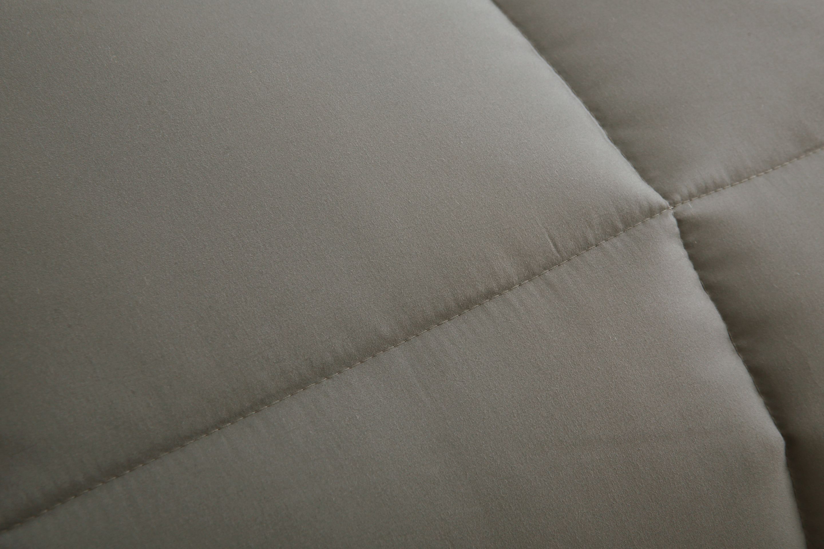 Close-up van het taupe 4-seizoenen dekbed van Zorgmatras, met zichtbare naden en vulling