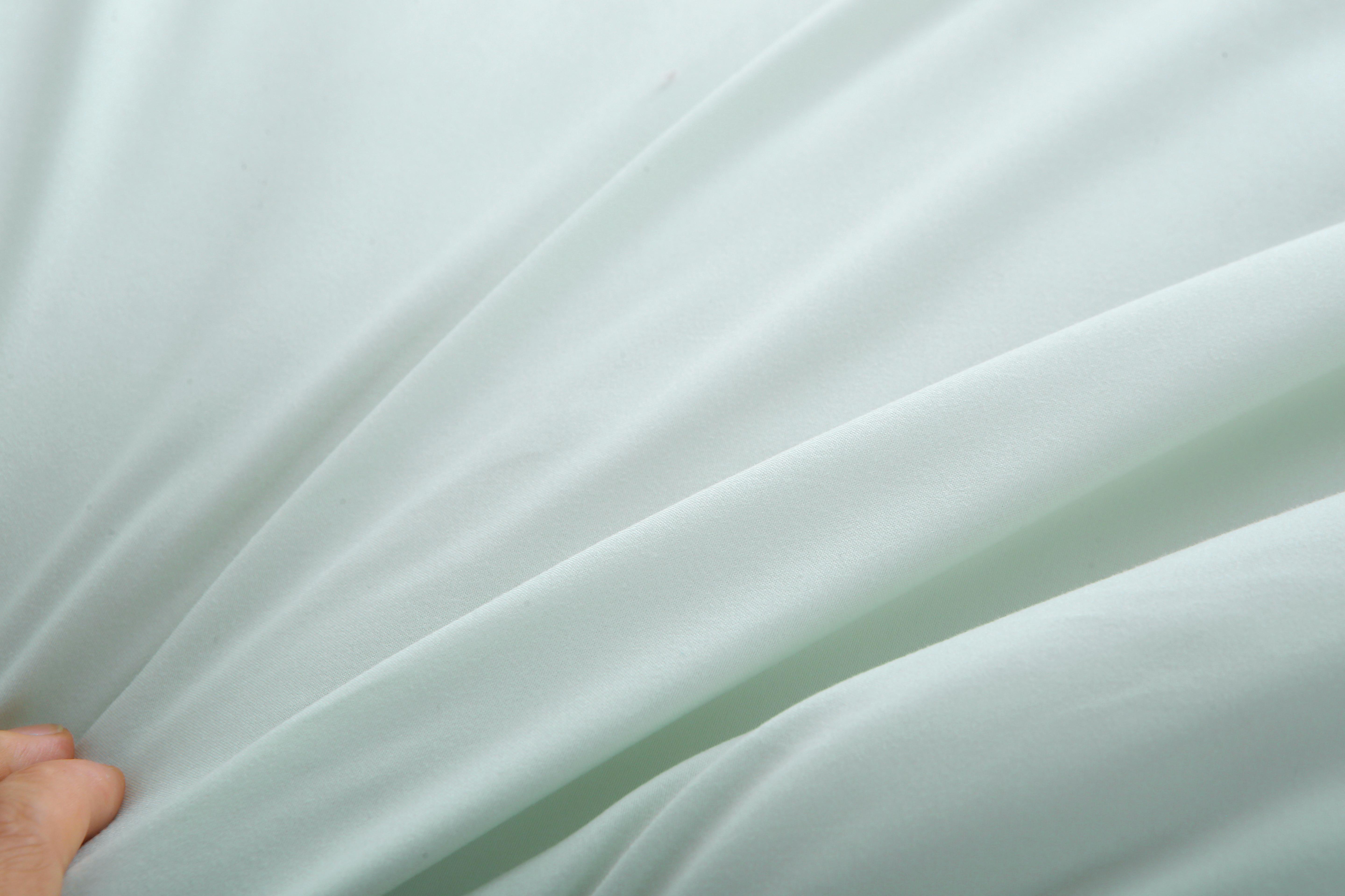 Close-up van de zachte, gladde stof van een lichtgroen verkoelend dekbed zonder overtrek