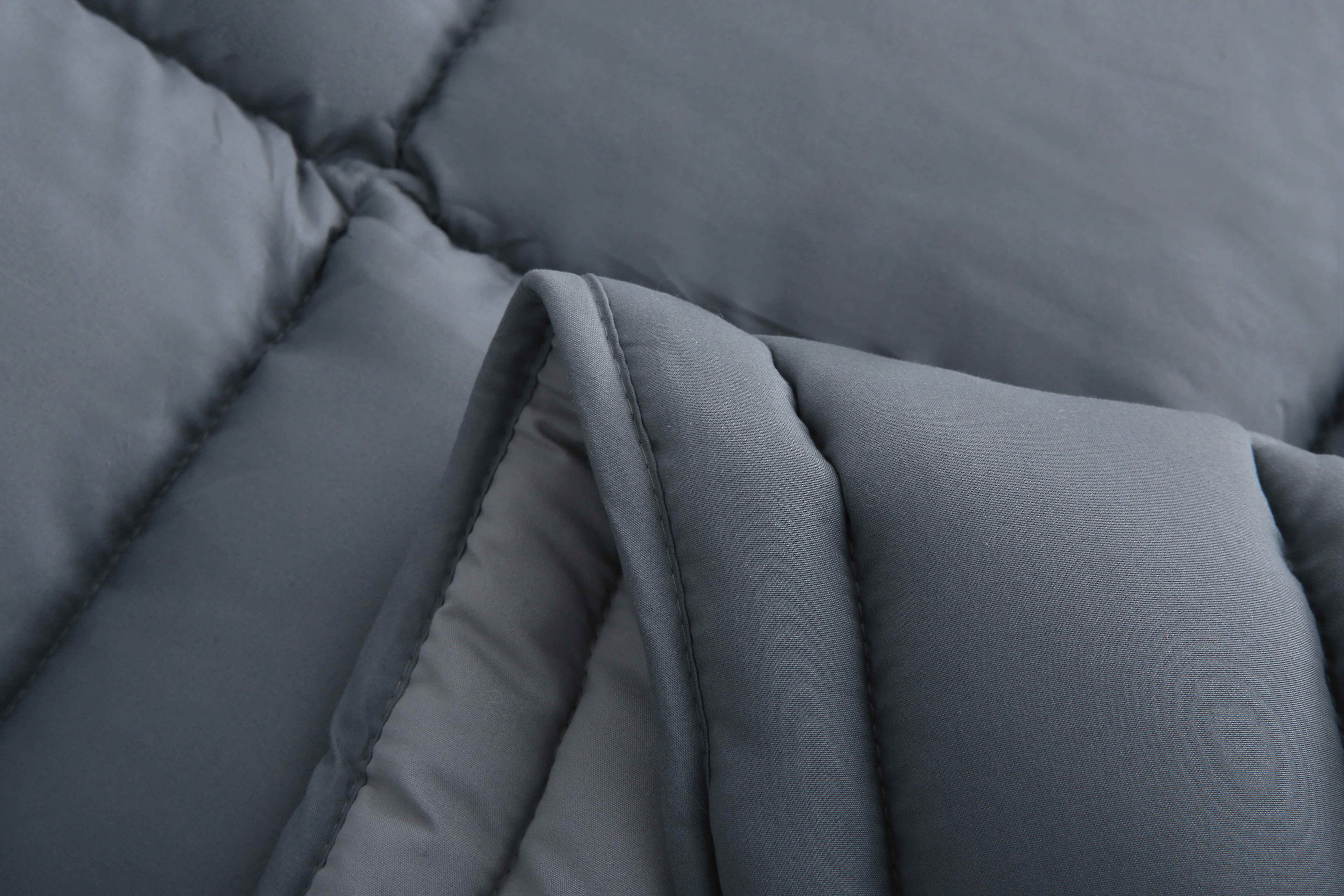 Close-up van antraciet dekbed zonder overtrek met zicht op de opening tussen de lagen