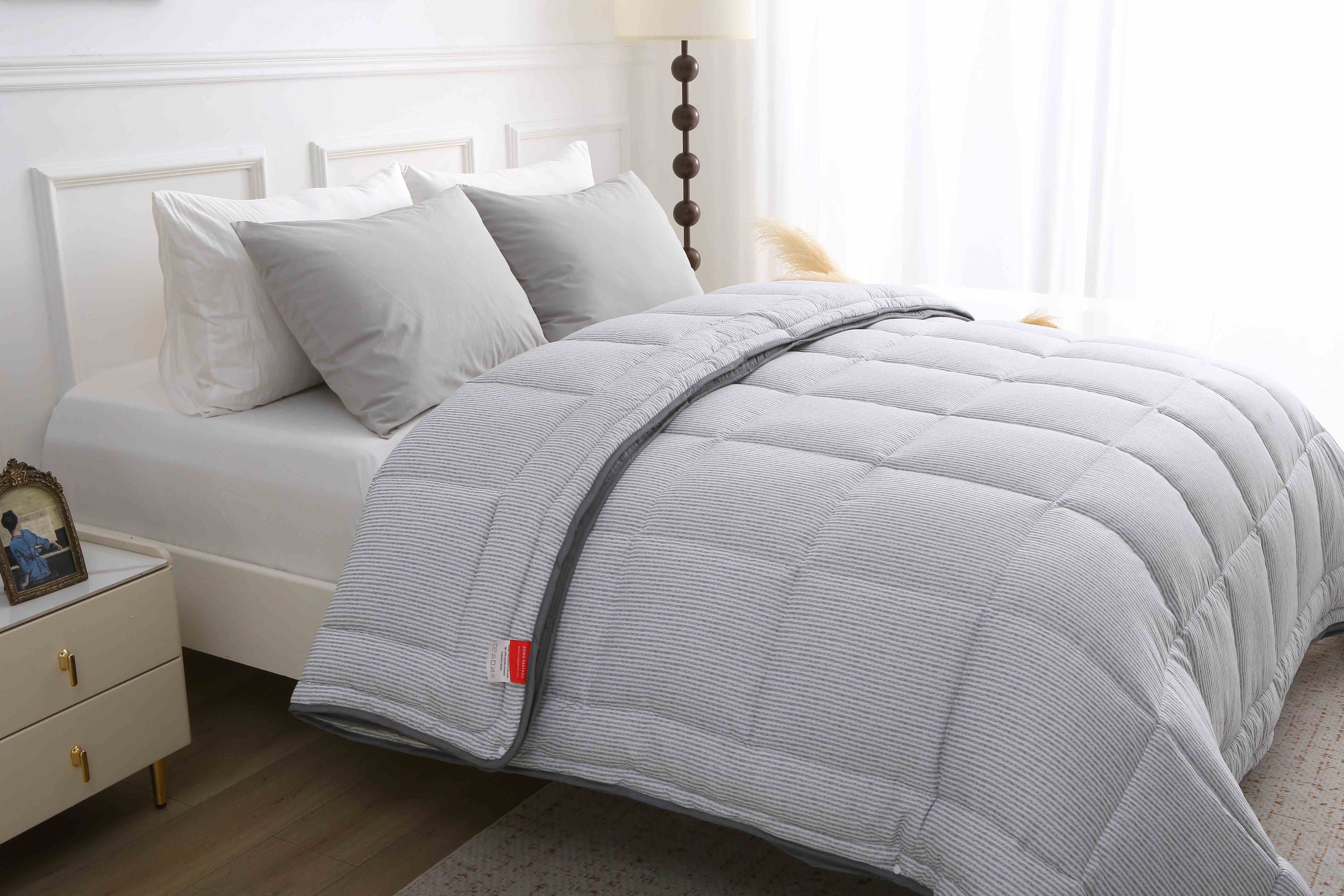 Detailopname van het grijs gestreepte dekbed zonder overtrek met vaste doorgestikte hoes