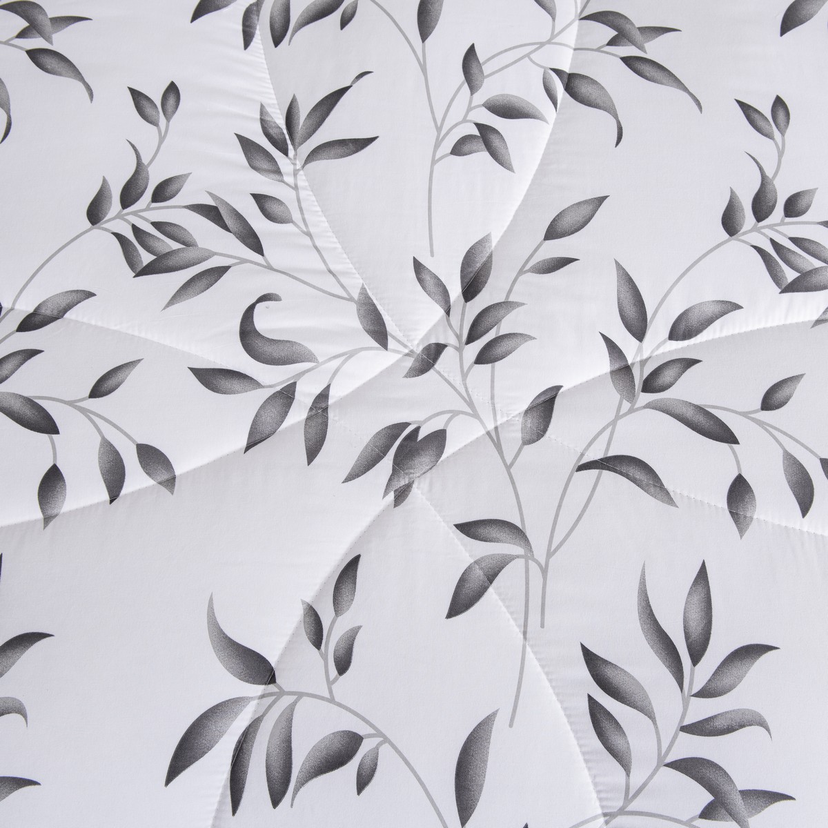 Detail van het 4‑seizoenen dekbed Nora met sierlijke bladprint en gestikte lijnen voor een luxe uitstraling